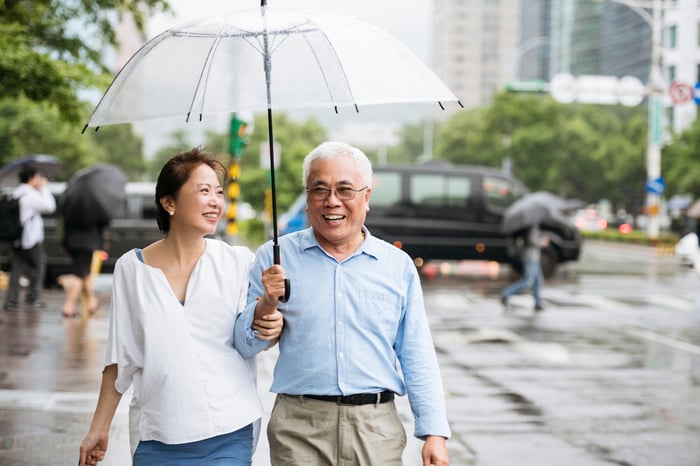A couple walks down a rainy street under an umbrella.