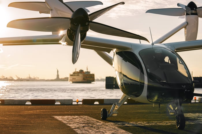 Joby's eVTOL aircraft sits on a landing pad in New York City with the Statue of Liberty in the background.