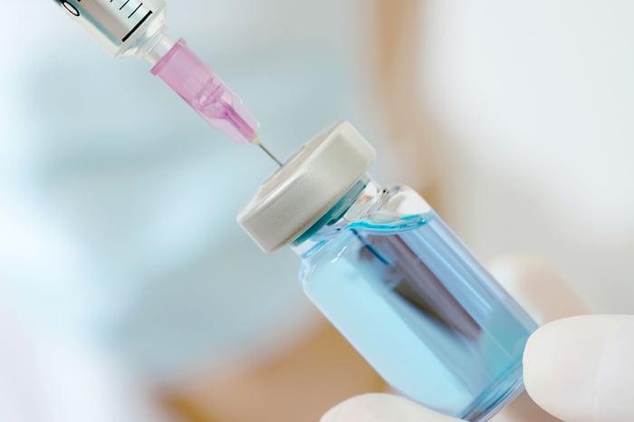 An injection is being withdrawn from a vial with a syringe.