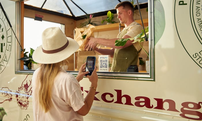 A woman scanning a QR code to pay with PayPal.