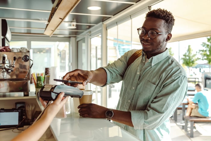 A person paying for a cup of coffee.