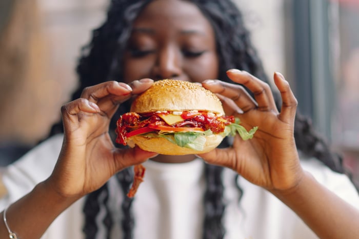 A person delicately holds a fast-food cheeseburger.