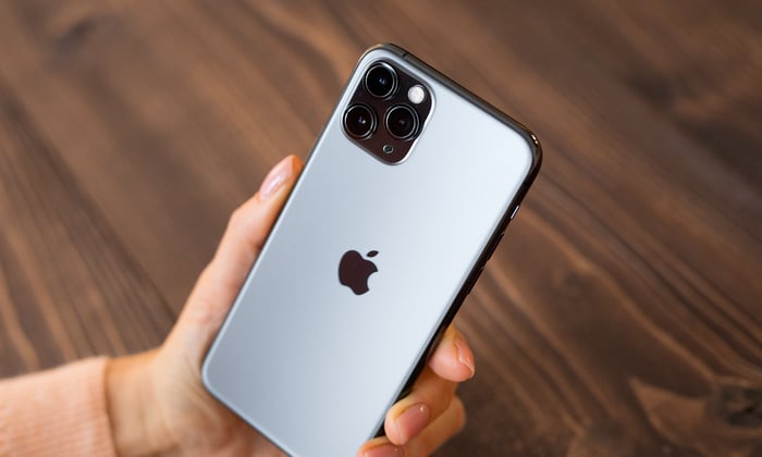 Person holding an iPhone with the Apple logo visible on the back.