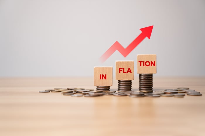 The word inflation printed on three wooden blocks below a red arrow. 