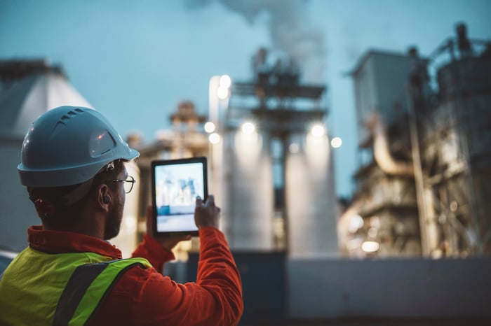 An oilfield worker taking a picture of a rig.