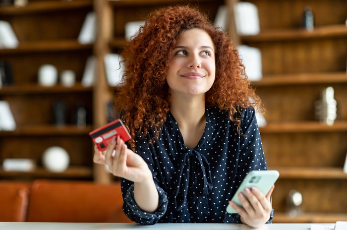A person holding a phone and a credit card.