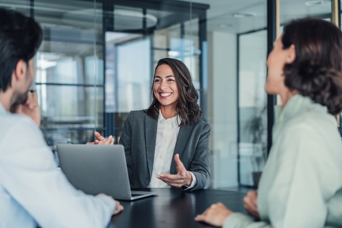 Professionals sitting and smiling in an office meeting.