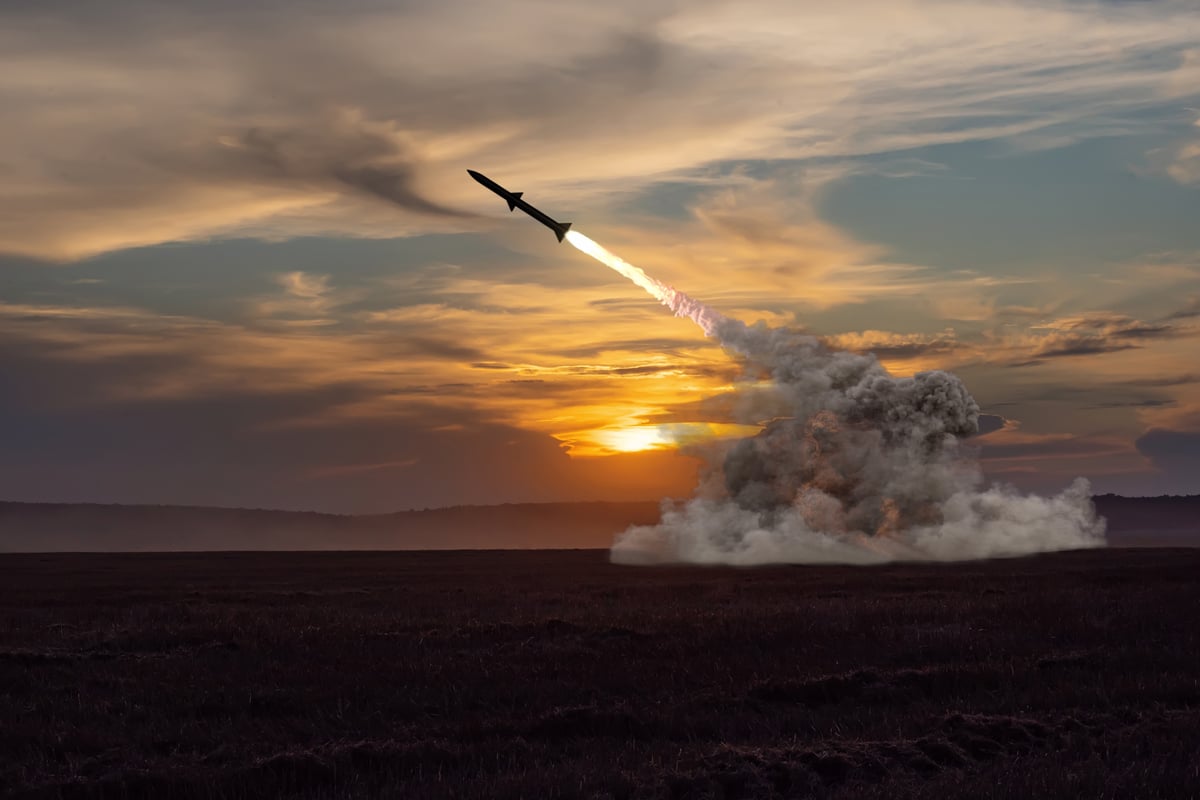 A plume of smoke emits from a missile launching into a cloudy sky.
