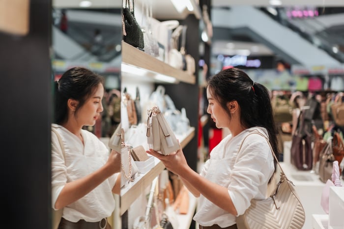 A shopper picking up a bag in a store.