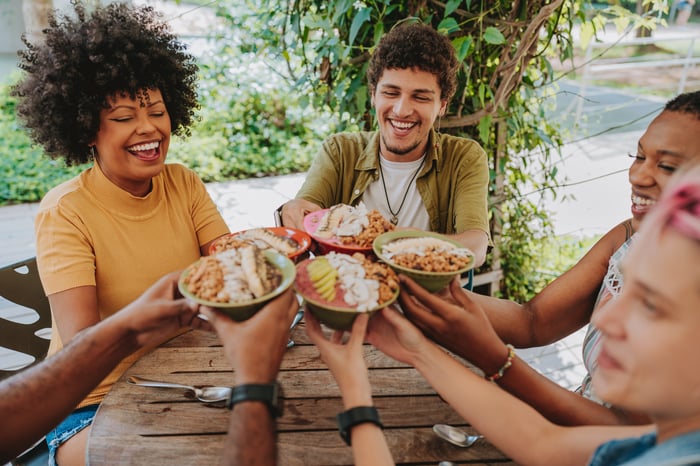 A group of people cheers their food bowls together. 