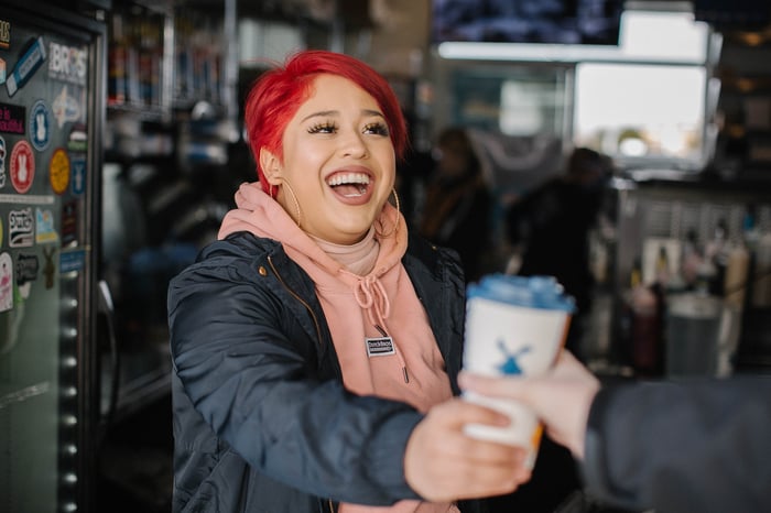 Dutch Bros broista giving over a beverage.