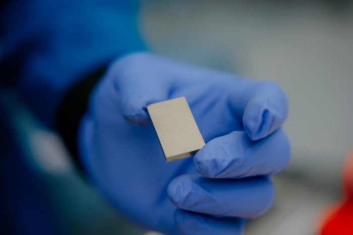 A gloved hand holds out a rare-earth magnet.