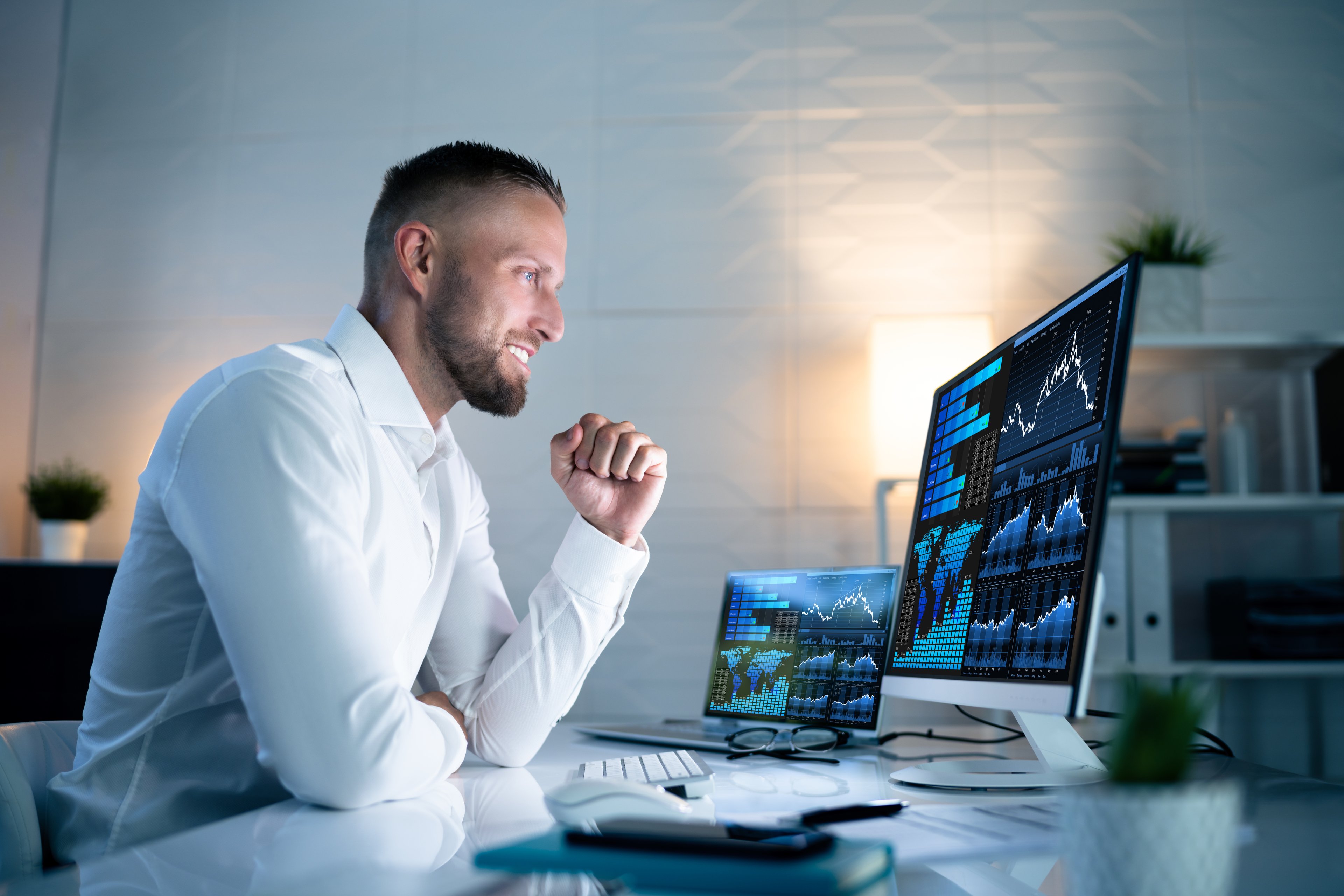 Stock investor looking at a computer screen with graphs celebrating success