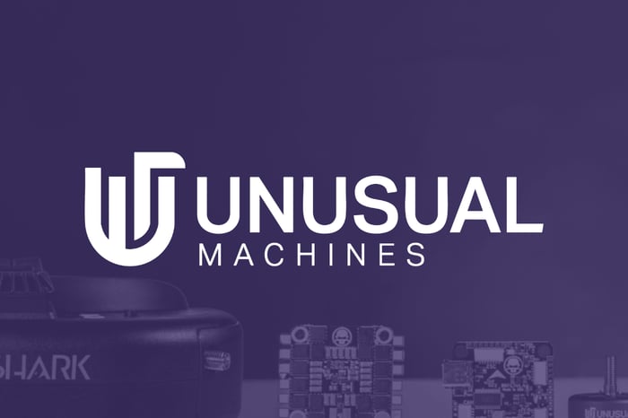 white logo of Unusual Machines with purple shaded view of its drone products in background. 