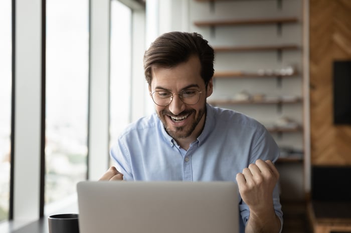An investor cheers behind a laptop.