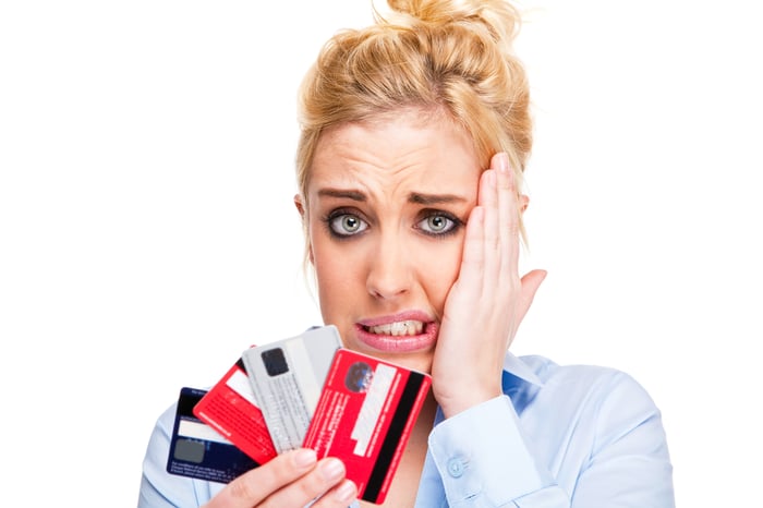 A person with a lot of credit cards in their hands, and a nervous look on their face. 