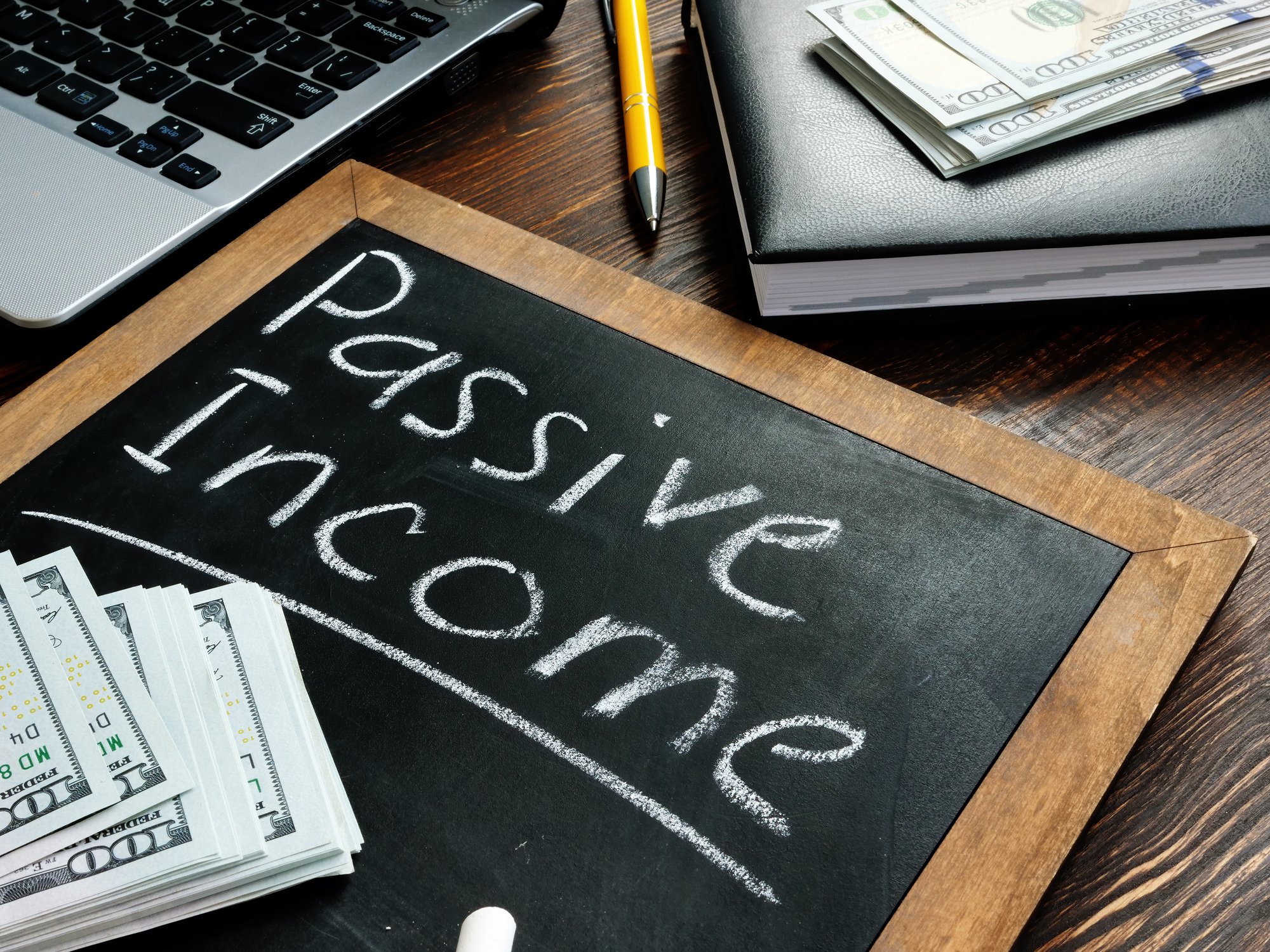 A small chalk board with passive income written out in near stacks of $100 bills.