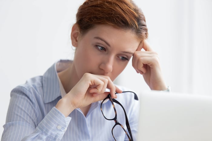 A person looks worried while looking at a computer.