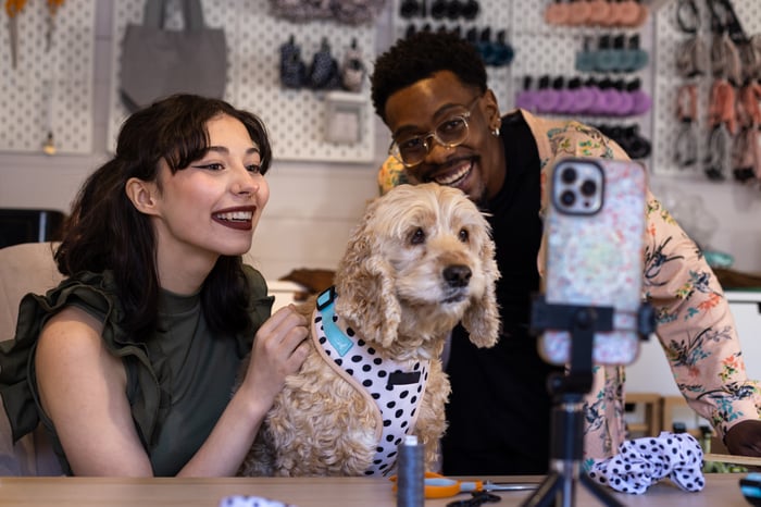 Two pet parents dressing up their dog for a photo. 