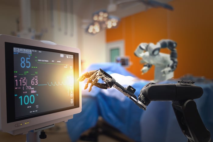 Robot hand reaching for medical readout screen.