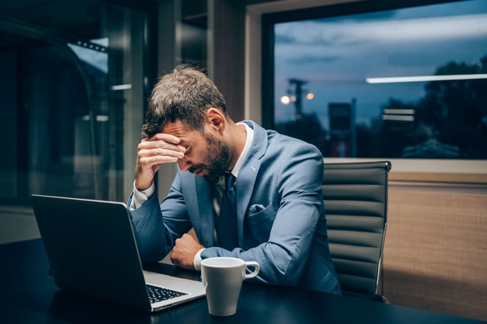 Frustrated person sitting next to a laptop.