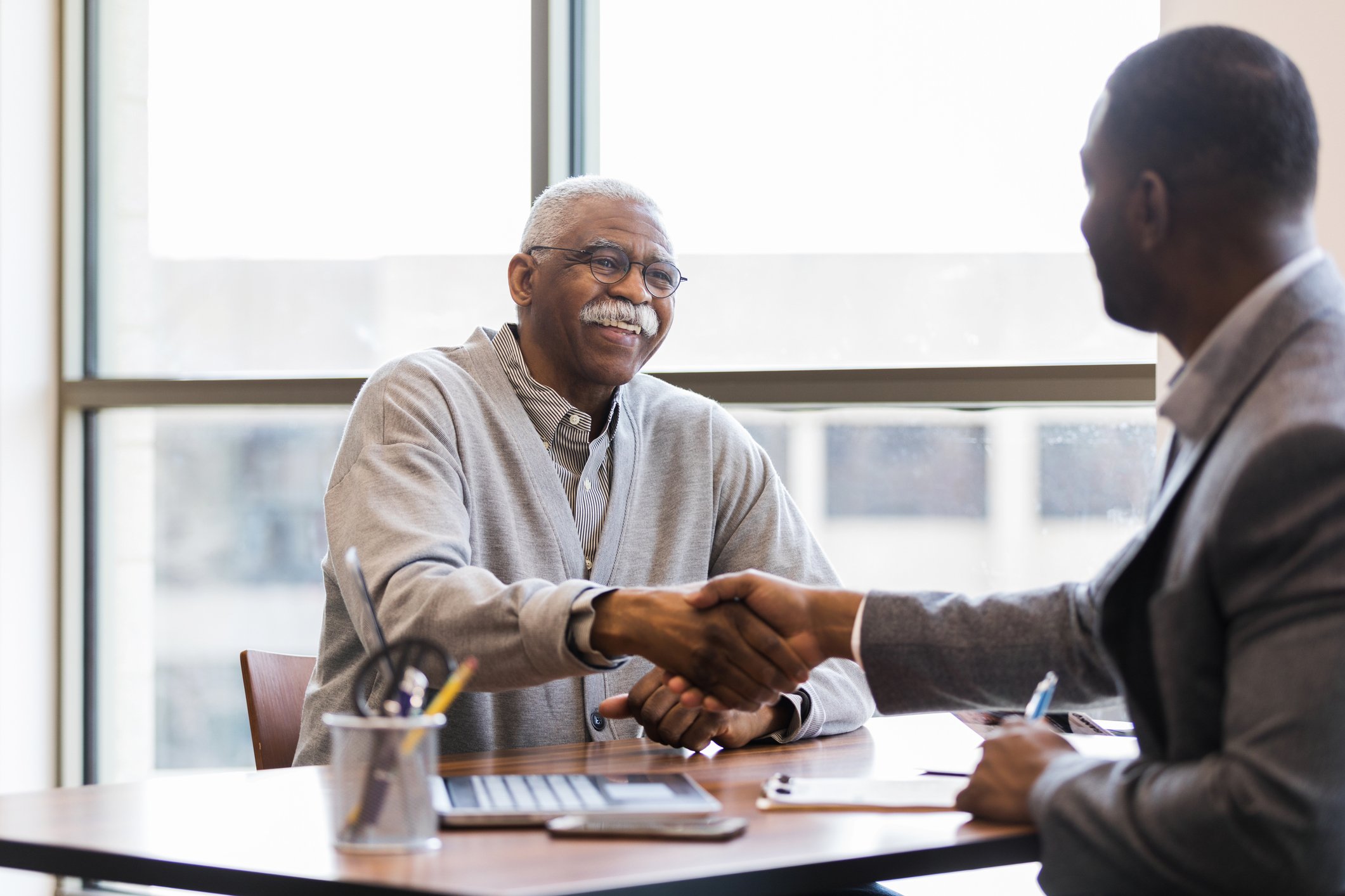 Two people shaking hands at a meeting.