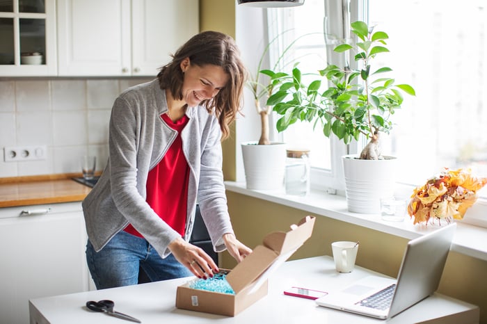 Person in kitchen, opening package.