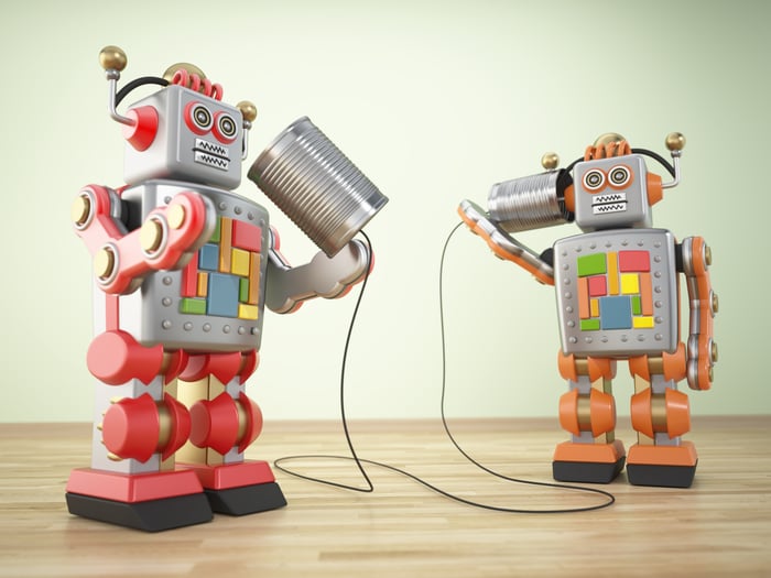A pair of toy robots hold a tin can-and-string phone.