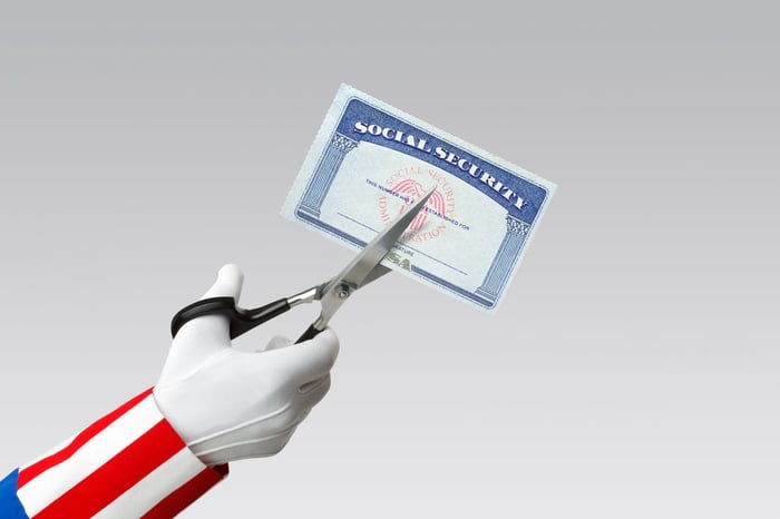 Uncle Sam's arm, with a pair of scissors in his hand and cutting a Social Security card. 