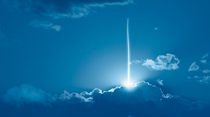 A rocket shoots into the blue sky. 