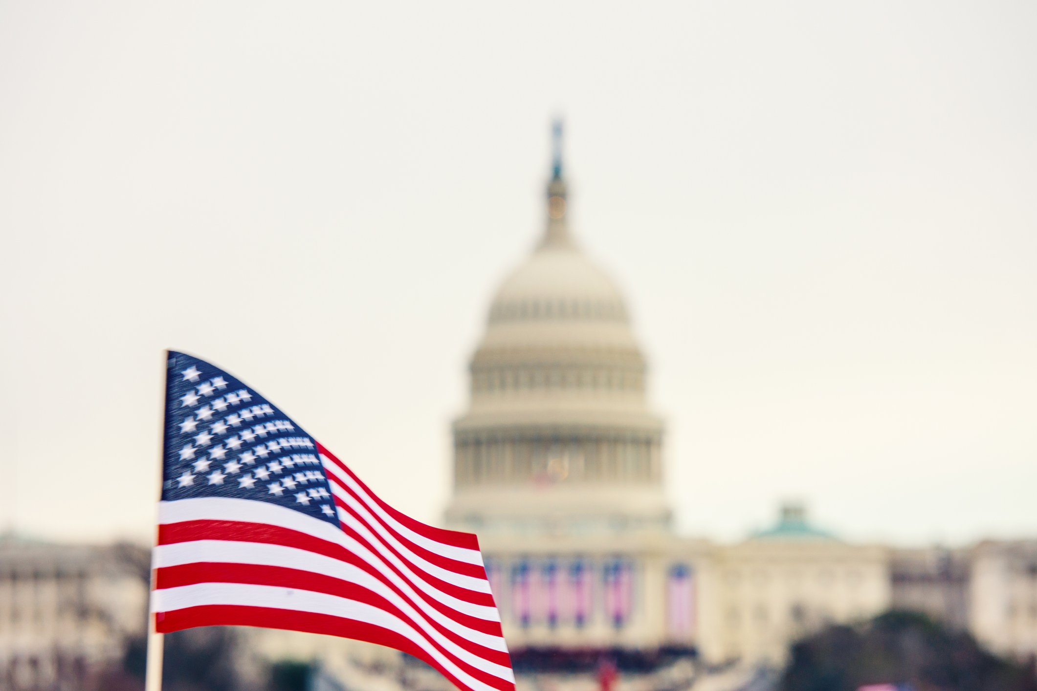 American flag being waved in front of the U.S. Capitol building