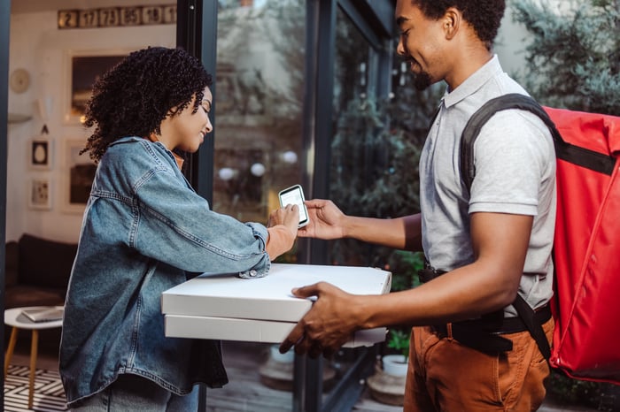 A person delivering pizza to a customer. 