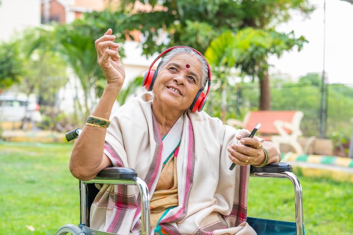 Someone is seated with a phone, looking up and smiling.