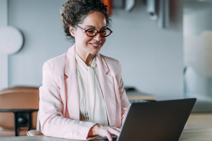 Professional smiling while working on a laptop.