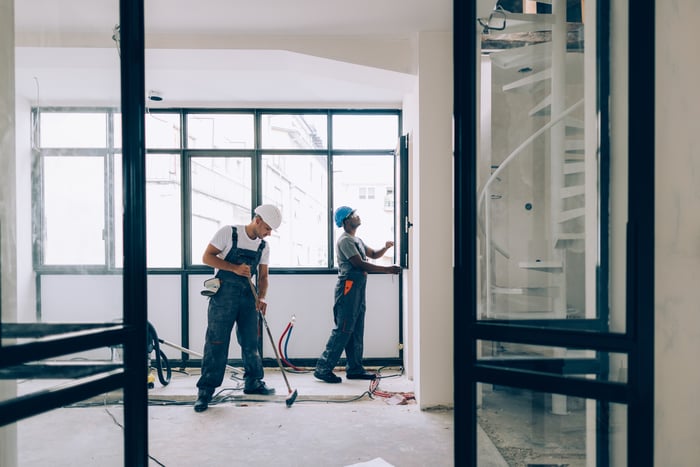 Two people working on a house.