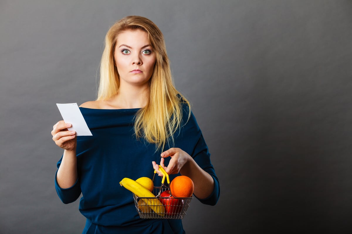 young woman holding produce and receipt upset about cost price sticker shock inflation-1200x800-5b2df79