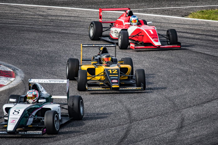 Three race cars circling a track.
