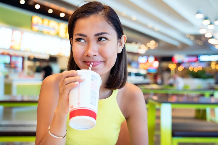 Person drinking at a food court.