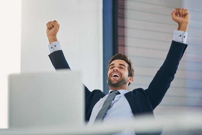 An investor cheers behind a laptop.