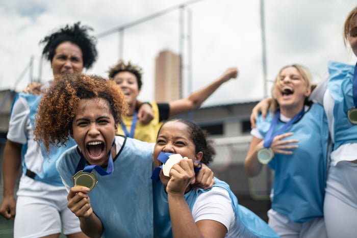A group of athletes holding up medals and cheering.