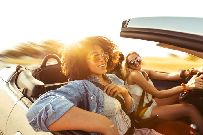 Two people driving in a convertible with the top down.