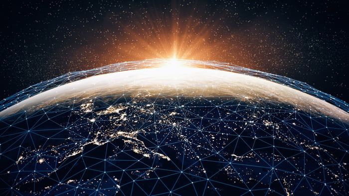 An interconnected grid covers Earth as the sun rises over the horizon, illustrating the growing importance of global connectivity.