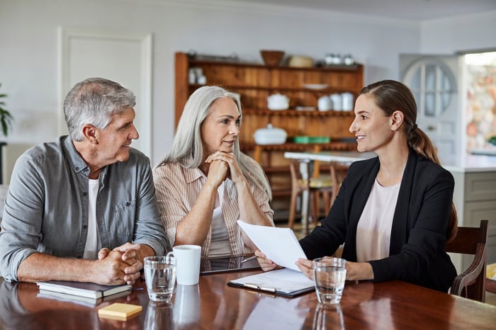 Three people sit at a table in a residential room.