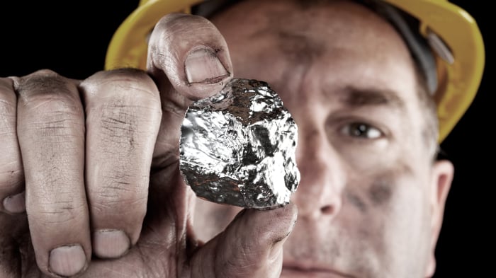 Man in mining hat holds a nugget of silver.