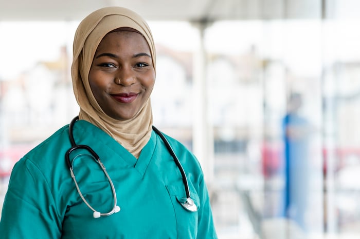 A healthcare worker is smiling with a stethoscope around their neck.