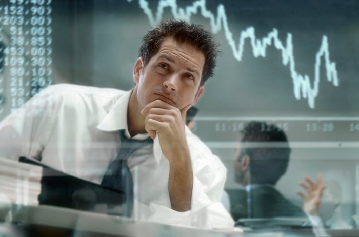 Serious-looking person reading chart and numbers on screen.