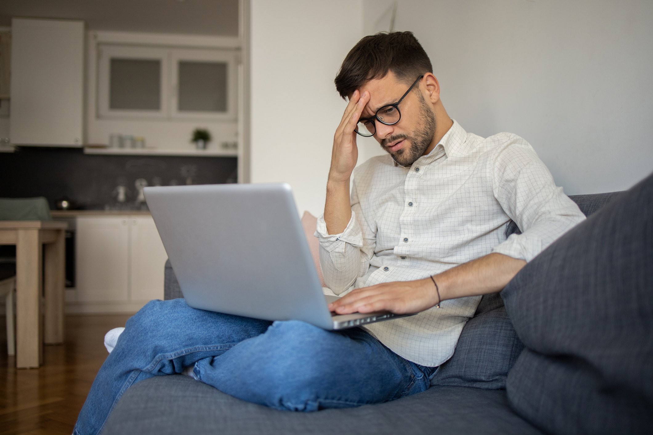 man 20s laptop holding head GettyImages-1433371688