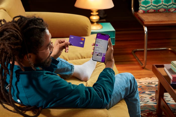 Person holding a Nu credit card and looking at the Nu app.