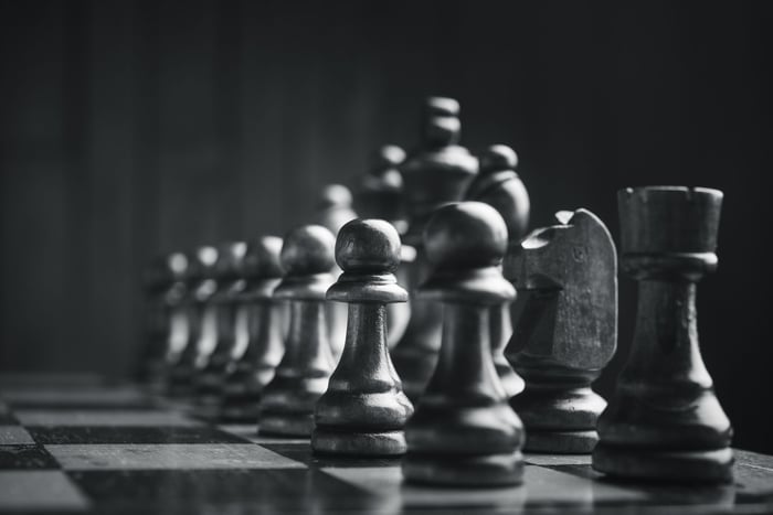 Chess pieces stand together, setup on a chess board. 