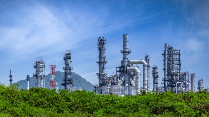 A power plant peaks out above a tree line.